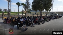 Soldiers stand next to detained migrants in Tripoli, Libya, in this photo released on Nov. 25, 2024. (Libyan Army 444th Combat Brigade/Handout via Reuters)