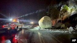 In this photo provided by Caltrans District 3, California Department of Transportation crews check large boulders that fell onto Highway 50 just east of Kyburz during a storm in El Dorado National Park, California, Jan. 1, 2023. 