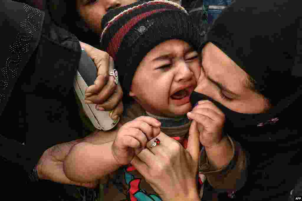 A child reacts as a health worker administers an Inactivated polio vaccine (IPV) during a polio vaccination campaign in Lahore, Pakistan.