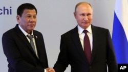 Presiden Rusia Vladimir Putin (kanan), berjabat tangan dengan Presiden Filipina Rodrigo Duterte selama pertemuan mereka di resor Laut Hitam di Sochi, Rusia, Kamis, 3 Oktober 2019 (Mikhail Klimentyev, Sputnik, Pool Pool Kremlin Foto melalui AP)