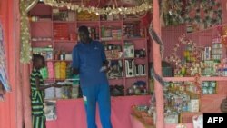 FILE - A shopkeeper hands an item to a girl in his shop in Juba, South Sudan, March 1, 2019.