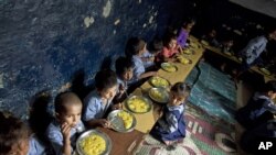 Children eat a meal at a school in a shanty neighborhood of New Delhi, India, Sept. 13, 2012.