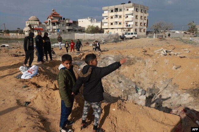 Warga Palestina berkumpul di dekat lubang besar di Rafah pada 18 Februari 2024, menyusul serangan udara Israel semalaman di kota perbatasan selatan Jalur Gaza. (Foto: AFP)