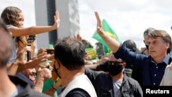 Presiden Brazil Jair Bolsonaro menyapa para pendukungnya di depan Istana Planalto di tengah pandemi virus corona (Covid-19), 24 Mei 2020. (Foto: Reuters)