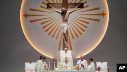 Pope Francis, standing, presides over a Holy Mass at the SportsHub National Stadium in Singapore.