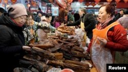 Customers select "la rou", a cured pork delicacy, at a market ahead of the Chinese Lunar New Year in Beijing, China January 16, 2020. Picture taken January 16, 2020. (REUTERS/Jason Lee)