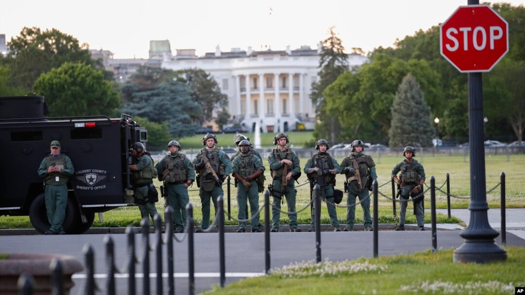 Law enforcement officers from Calvert County Maryland Sheriff's Office standing on the Ellipse, area just south of the White House in Washington, as they watch demonstrators protest the death of George Floyd, Sunday, May 31, 2020. 