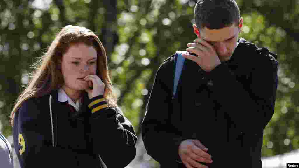 Mourners weep as they view flowers left in memory of his Lee Rigby outside an army barracks near the scene of his killing in Woolwich, southeast London May 23, 2013.