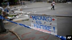 Un cartel en rechazo al presidente Nicolás Maduro es desplegado en una calle de Caracas, Venezuela, el miércoles, 26 de julio de 2017, como parte de una barricada en el paro de 48 horas convocado por la oposición.
