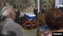 People stand in front of the flag draped coffin of former Israeli Prime Minister Yitzhak Shamir as it lies in state at the parliament in Jerusalem, July 2, 2012. 