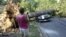 A woman takes photograph of Mike Wolfe's pick-up truck as it lies under a fallen tree in front of his house after a severe storm in Falls Church, Va., June 30, 2012.