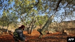 FILE - A Syrian rebel fighter prepares to fire a rocket toward a position held by regime forces, in the southern countryside of Syria's rebel-held Idlib province, Nov. 13, 2020.