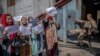 FILE - A Taliban fighter watches as Afghan women hold placards during a demonstration demanding better rights for women in front of the former Ministry of Women Affairs in Kabul, Sept. 19, 2021.