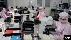 FILE - This photo taken on April 29, 2024 shows employees working at a semiconductor chips factory in Huai'an, in eastern China's Jiangsu province. 