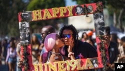 Daisa Chantel besa a Anthony Beltran mientras se toman una foto para celebrar el Juneteenth en Leimert Park en Los Ángeles el sábado 18 de junio de 2022.