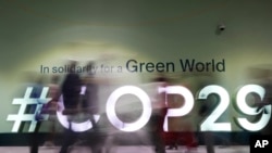 Personas caminan frente a un cartel sobre la Cumbre Climática de la ONU COP29, el 13 de noviembre de 2024, en Bakú, Azerbaiyán.