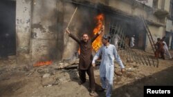 Un manifestante grita consignas antiestadounidenses frente a un cine incendiándose en el "día de amor" a Mahoma en Peshawar.