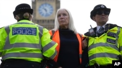 FILE- An activist from the group Just Stop Oil is arrested by police officers as they slow the traffic, marching on a road, in London, on Oct. 30, 2023. 