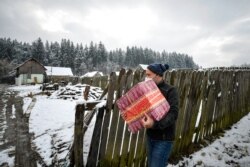 Valeriu Nicolae carries a box containing basic food, hygiene and medicinal products in Nucsoara, Romania, Jan. 9, 2021.