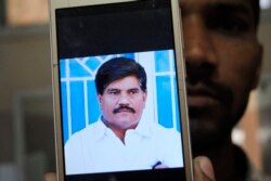 An employee of a local television channel shows a picture of slain journalist Aziz Memon on his mobile, after a demonstration to condemn his killing, in Hyderabad, Pakistan, Monday, Feb. 17, 2020. The body of Memon was found dumped in a canal just…