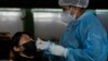 ARCHIVO - Un trabajador de la salud toma una muestra del interior de la nariz de una mujer para una prueba de COVID-19 en un centro de pruebas en La Paz, Bolivia, el miércoles 20 de julio de 2022. 