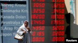 FIILE - A woman walks past a currency exchange office in downtown Istanbul, June 21, 2013. 