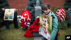 Một phu nữ Nga cầm ảnh chân dung Joseph Stalin đứng gần ngôi mộ của cựu lãnh đạo Xô Viết trong ngày sinh nhật lần thứ 136 của ông ở Moscow, Nga, ngày 21/12/2015. 