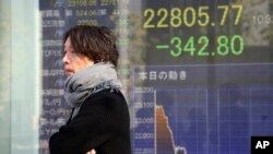 A man walks by an electronic stock board of a securities firm in Tokyo, Nov. 21, 2019.