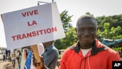 Un partisan tient une pancarte en français lisant «Vive la transition», à l'extérieur où une cérémonie de prestation de serment du président et du vice-président de transition a eu lieu, dans la capitale Bamako, Mali, vendredi 25 septembre 2020. 