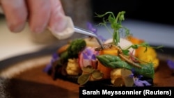 French chef Laurent Veyet puts a cricket on a dish in his restaurant Inoveat serving insect-based food in Paris, France, May 12, 2021. (REUTERS/Sarah Meyssonnier)