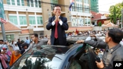 FILE - Cambodia's main opposition Cambodia National Rescue Party Deputy President and National Assembly Deputy President Kem Sokha greets to his supporters outside the Phnom Penh Municipality Court in Phnom Penh, Wednesday, April 8, 2015.