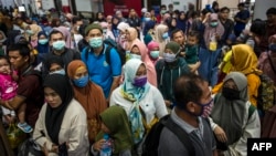 Para penumpang kereta api mengenakan masker sebagai pencegahan virus corona, di stasiun di Surabaya, 15 Maret 2020. (Foto: AFP)