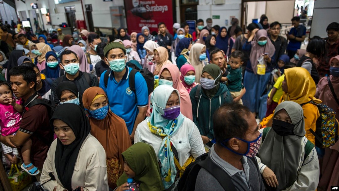 Para penumpang kereta api mengenakan masker sebagai pencegahan virus corona, di stasiun di Surabaya, 15 Maret 2020. (Foto: AFP)