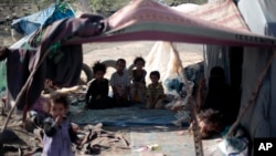 FILE - Displaced children pose for a photo as they sit in their family's tent at a camp for internally displaced people in the outskirts of Sana'a, Yemen, June 8, 2016.