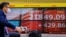 A cyclist wearing a face mask rides past an electric quotation board displaying the morning numbers of the Nikkei 225 Index on the Tokyo Stock Exchange in Tokyo on May 28, 2020. 
