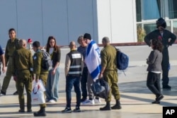 Berbalut bendera Israel, warga negara Amerika-Israel Keith Siegel, yang disandera Hamas di Gaza sejak 7 Oktober 2023, tiba di Rumah Sakit Ichilov di Tel Aviv, Israel, Sabtu, 1 Februari 2025. (Foto: AP)