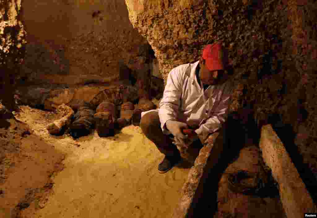 A Egyptian archaeologist is seen next to a coffin with mummy inside a tomb during the presentation of a new discovery at Tuna el-Gebel archaeological site in Minya Governorate, Egypt, Feb. 2, 2019. 