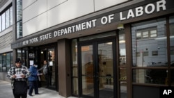 FILE - Visitors to the Department of Labor are turned away at the door by personnel due to closures over coronavirus concerns on March 18, 2020, in New York. 