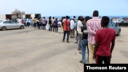 Migrants line up to receive food packages distributed by United Nations High Commissioner for Refugees (UNHCR) in Tripoli. Libya, on May 12, 2020.