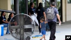 José Gutiérrez y su nieto Kamen Gutiérrez caminan hacia una estación de enfriamiento en la Iglesia Lakewood en Houston, Texas, EEUU, el martes 9 de julio de 2024.