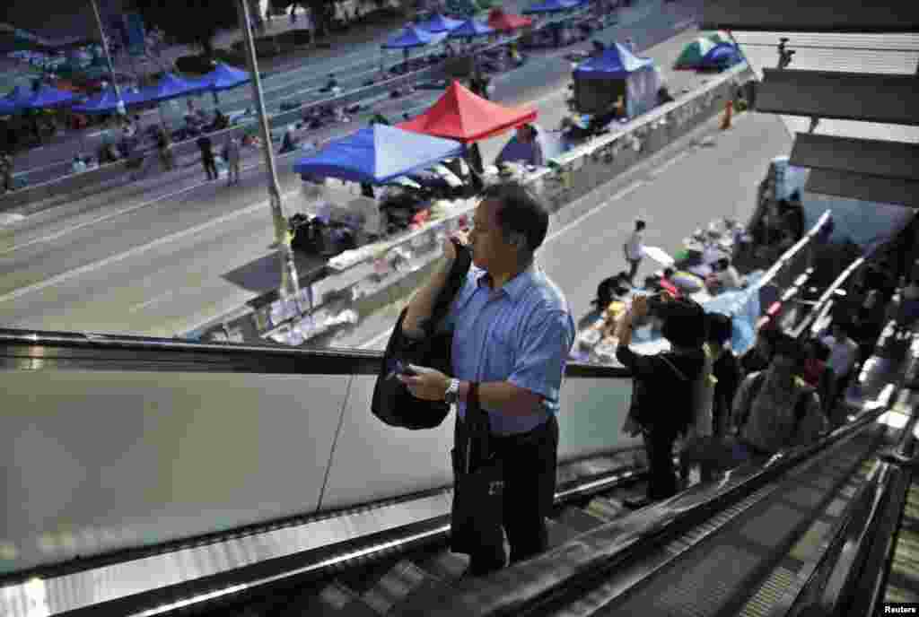 Government employees arrive to work as they walk along an area occupied by protesters outside of the government headquarters building in Hong Kong, Oct. 6, 2014. 