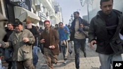 Protestors run away from tear gas during a demonstration against former Tunisian President Zine El Abidine Ben Ali in the center of Tunis, 17 Jan 2011