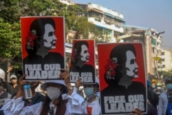 FILE - Anti-coup protesters carry pictures of deposed Myanmar leader Aung San Suu Kyi, in Yangon, Myanmar, March 2, 2021.