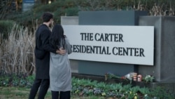 Sepasang suami istri berdiri di depan papan nama The Carter Presidential Center, setelah meninggalnya mantan Presiden Amerika Serikat Jimmy Carter pada usia 100 tahun, di Atlanta, Georgia, AS, 29 Desember 2024. (Elijah Nouvelage/REUTERS)