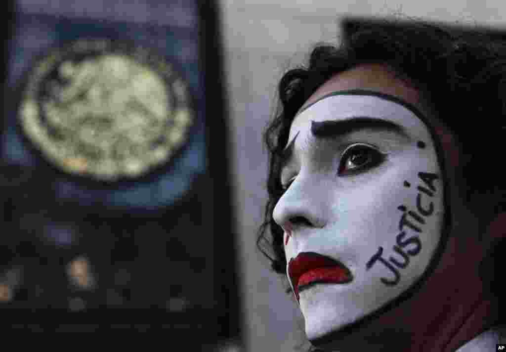 A student wearing white clown makeup with the Spanish word for &quot;justice&quot; written on the side of his face, stands outside the Attorney General&#39;s office in Mexico City, Nov. 22, 2014, following a massive gathering in the capital&#39;s main plaza Zocalo to demand that authorities find 43 missing college students.