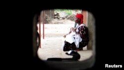 FILE - A woman sits with her child at a health clinic in Bujumbura, Burundi, Apr. 18, 2006. More than one million people die from malaria every year, almost 90 percent are in Africa. 