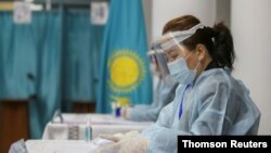 A member of a local electoral commission wearing protective gear checks lists of voters during a parliamentary election in Almaty, Kazakhstan, Jan. 10, 2021.