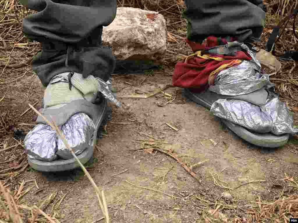 Juan Rosales un venezolano que caminó hasta la frontera entre Colombia y Ecuador, usa lo que puede para calentarse los pies, tras quedarse sin zapatos en su travesía. Ipiales, Colombia, 11 de septiembre de 2019. Foto: Celia Mendoza - VOA. 