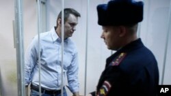 Aktivis oposisi Rusia, Alexei Navalny (kiri) memasuki kurungan di sebuah pengadilan di Moskow, Rusia (Foto: dok). Alexei Navalny, telah mengajukan permohonan agar lebih cepat dibebaskan dari penjara, supaya ia dapat menghadiri upacara pemakaman politisi oposisi, Boris Nemtsov.