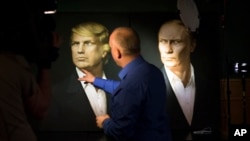 Seorang jurnalis menunjuk ke potret Donald Trump dan Vladimir Putin dalam acara siaran langsung pemilihan presiden di pub Union Jack di Moskow, Rusia (9/11). (AP/Alexander Zemlianichenko)